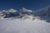 a person on skis is sitting near snow on the ground with mountains in the background