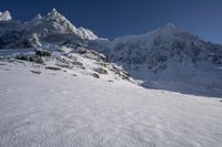 a person on skis is sitting near snow on the ground with mountains in the background