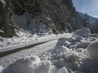 a dirt road near the edge of a snow covered forest in the day light from above the mountain