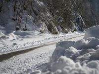 a dirt road near the edge of a snow covered forest in the day light from above the mountain