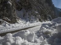 a dirt road near the edge of a snow covered forest in the day light from above the mountain