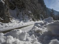 a dirt road near the edge of a snow covered forest in the day light from above the mountain