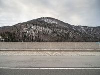 the side of a snowy road with mountains in the background and a sky background and one road has snow on it