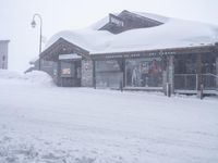 a large amount of snow is piled over the building in the center of the street