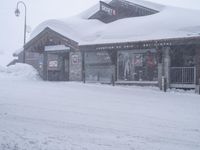 a large amount of snow is piled over the building in the center of the street