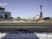 snow covered area in front of building with a clock tower and street lights in the background