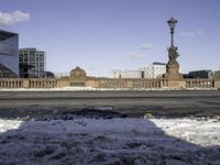 snow covered area in front of building with a clock tower and street lights in the background