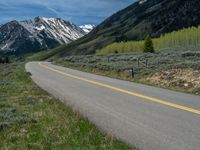 the road is paved with yellow markings and has a snowy mountain range in the background