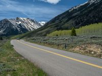 the road is paved with yellow markings and has a snowy mountain range in the background