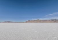 lone motorbike on a snow covered desert surface near mountains and sky line in distance