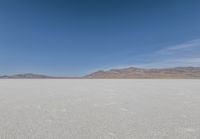 lone motorbike on a snow covered desert surface near mountains and sky line in distance