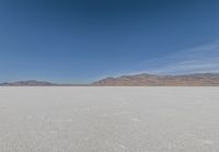 lone motorbike on a snow covered desert surface near mountains and sky line in distance