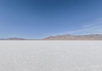 lone motorbike on a snow covered desert surface near mountains and sky line in distance