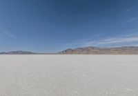 lone motorbike on a snow covered desert surface near mountains and sky line in distance