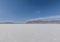 lone motorbike on a snow covered desert surface near mountains and sky line in distance