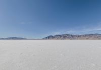 lone motorbike on a snow covered desert surface near mountains and sky line in distance