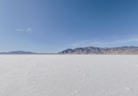 lone motorbike on a snow covered desert surface near mountains and sky line in distance