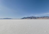 lone motorbike on a snow covered desert surface near mountains and sky line in distance