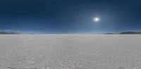 a panoramic image of an expanse of snow in the desert under a bright sun