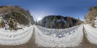 a pair of dirt roads are snow covered with snow and trees on the side of the road