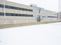 a view of a snow covered driveway next to building with large windows and shutters