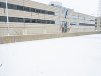 a view of a snow covered driveway next to building with large windows and shutters