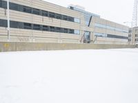 a view of a snow covered driveway next to building with large windows and shutters