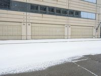 a view of a snow covered driveway next to building with large windows and shutters