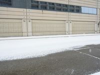 a view of a snow covered driveway next to building with large windows and shutters