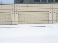 a view of a snow covered driveway next to building with large windows and shutters