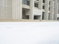 a view of a snow covered driveway next to building with large windows and shutters