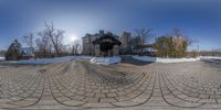 this circular view shows a snow covered driveway and snow covered building, in the background