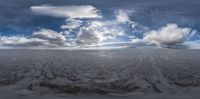 a snow covered field with some clouds in the background of the field is covered in ice