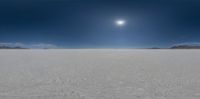 snow covered field with sun behind the sky with cloud and blue sky over horizon to left and right of photograph