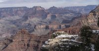 a group of people watching the grand canyon in the snow from a viewpoint on a hill