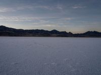 snow covering the ground with mountains in the background under a cloudy sky or evening sky