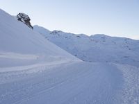 a person walking down the side of a snow covered hill with a skiier on