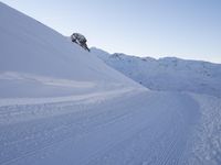 a person walking down the side of a snow covered hill with a skiier on