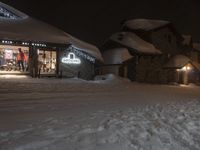 a hotel on a street covered in snow at night with light shining through windows in the corner