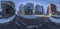 a snow covered intersection of an urban city street in the wintertime and a fish eye lens