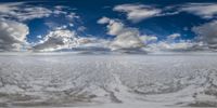 snow - covered land in the middle of the clouds with snow coming from it and a view of a distant horizon