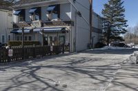 a street that has several parking meters next to some buildings on it near snow covered lawns