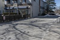 a street that has several parking meters next to some buildings on it near snow covered lawns