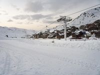 the cable car is near a snow covered mountain, where there are skis and snowboard ramps