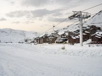 the cable car is near a snow covered mountain, where there are skis and snowboard ramps