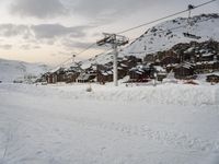 the cable car is near a snow covered mountain, where there are skis and snowboard ramps