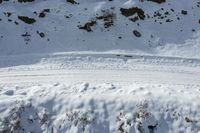 a snow covered mountain and tracks in the snow with two people skiing up it while on skis