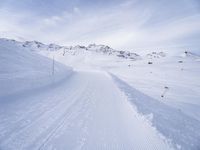 snow covered slope in the middle of a ski area as people ski on it near ski lift