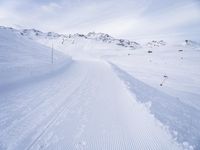 snow covered slope in the middle of a ski area as people ski on it near ski lift