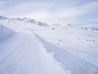 snow covered slope in the middle of a ski area as people ski on it near ski lift